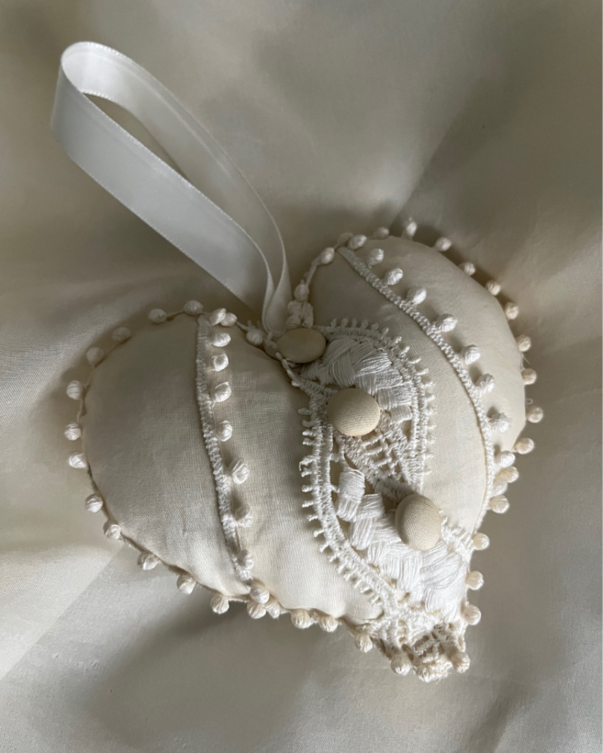 Beige 4x4 heart-shaped wedding ornament made from a repurposed wedding gown. Lace down the front with three buttons sewed on the top.